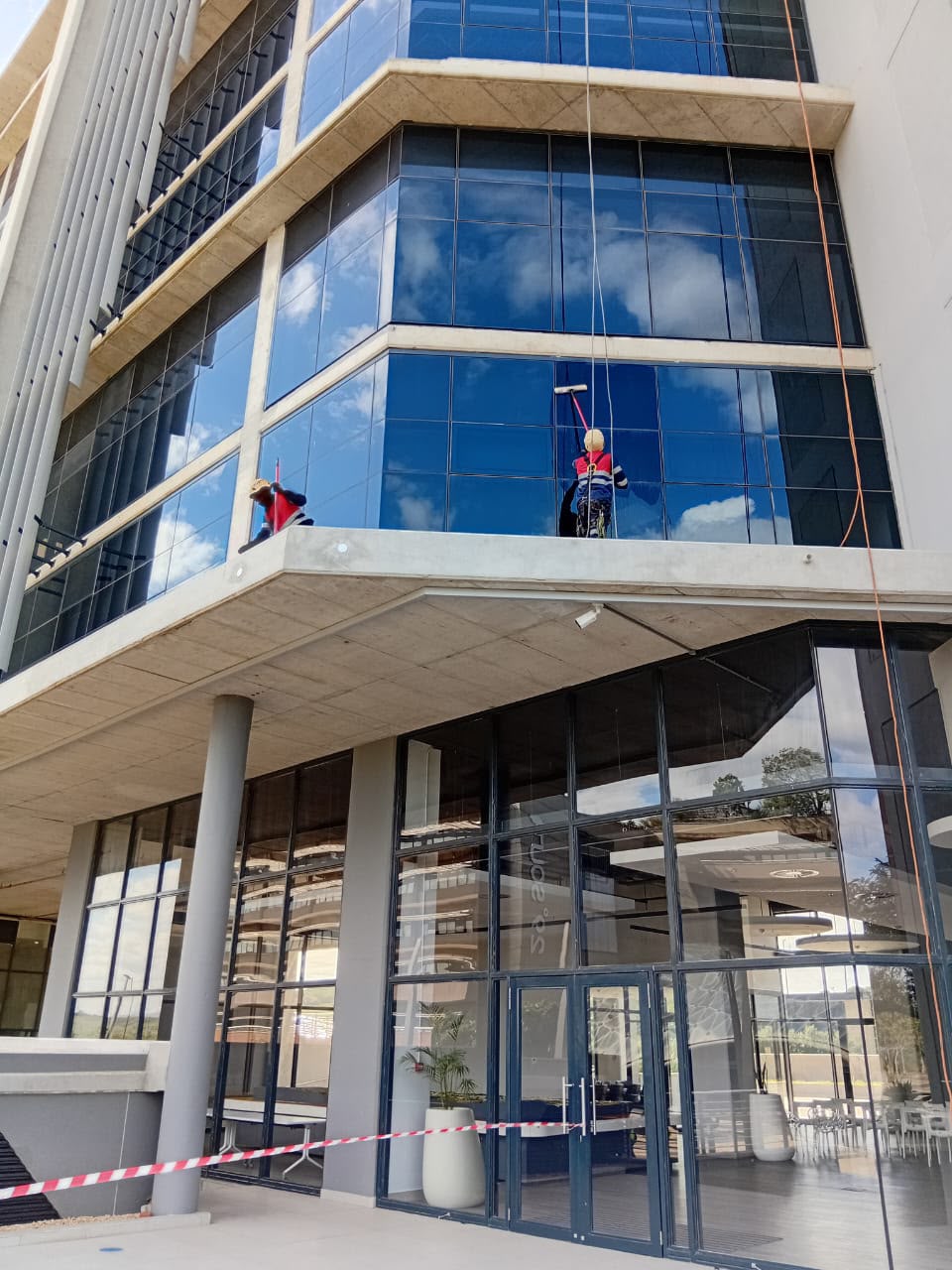 Rope access technicians cleaning a glass office tower
