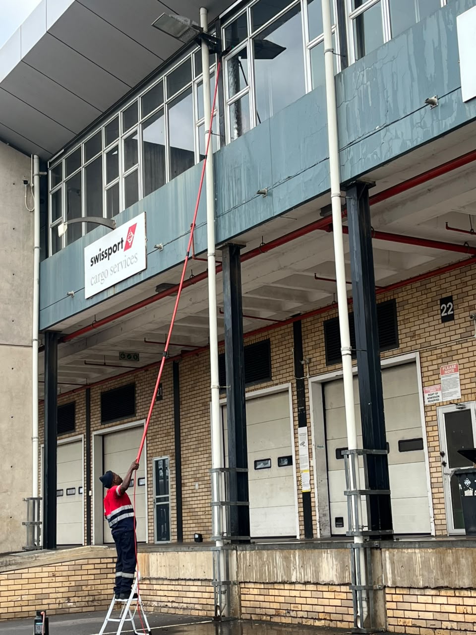 Technician cleaning high commercial windows with a water-fed pole